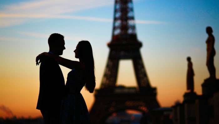 couple embrace in front of eiffel tower in paris